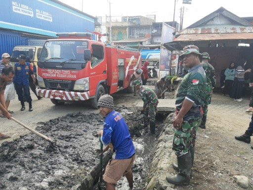 Batuud Koramil 05/Dua Pitue bersama personel TNI dan warga membersihkan saluran air yang dipenuhi lumpur di Pasar Tanru Tedong, Sidrap, dengan didukung armada pemadam kebakaran.