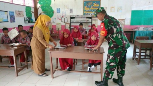 Babinsa TNI Sidrap bersama guru membagikan makanan bergizi kepada siswa-siswi SD di ruang kelas.