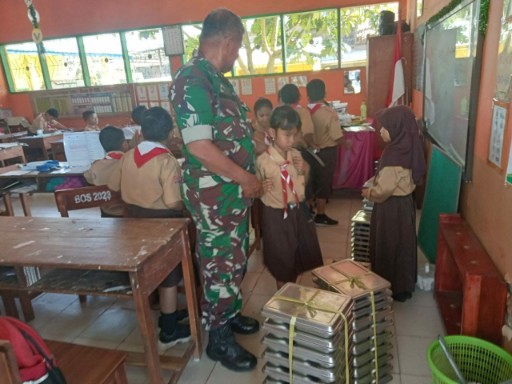 Babinsa Kodim 1420 Sidrap mendampingi siswa membagikan makanan bergizi di ruang kelas.