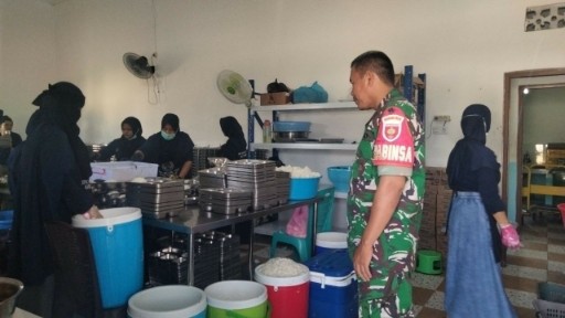 Babinsa TNI memantau persiapan makanan bergizi untuk siswa.