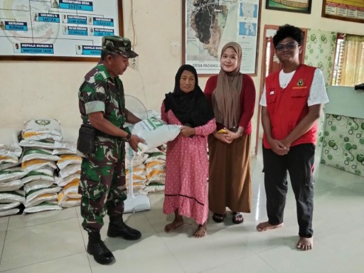 Babinsa menyerahkan bantuan pangan kepada warga di sebuah balai desa di Kabupaten Sidenreng Rappang.