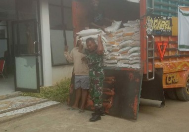 Personel Babinsa Dua Pitue bantu angkut beras bantuan dari truk distribusi.