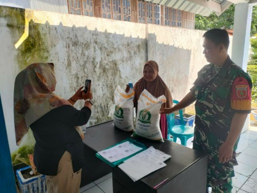 Babinsa Kodim 1420/Sidrap mendampingi penyaluran bantuan beras kepada warga.