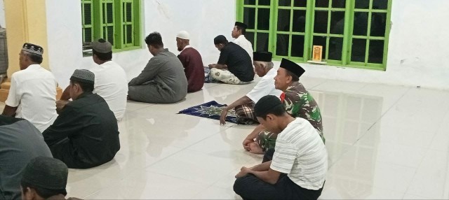 Seorang Babinsa duduk bersama warga saat mengikuti salat subuh berjamaah di masjid.