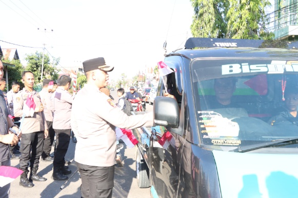 Kapolres Sidrap membagikan bendera merah putih kepada pengendara di jalan raya.