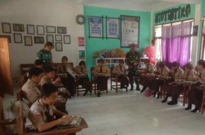 Babinsa mendampingi siswa saat pembagian makan bergizi gratis di sekolah.