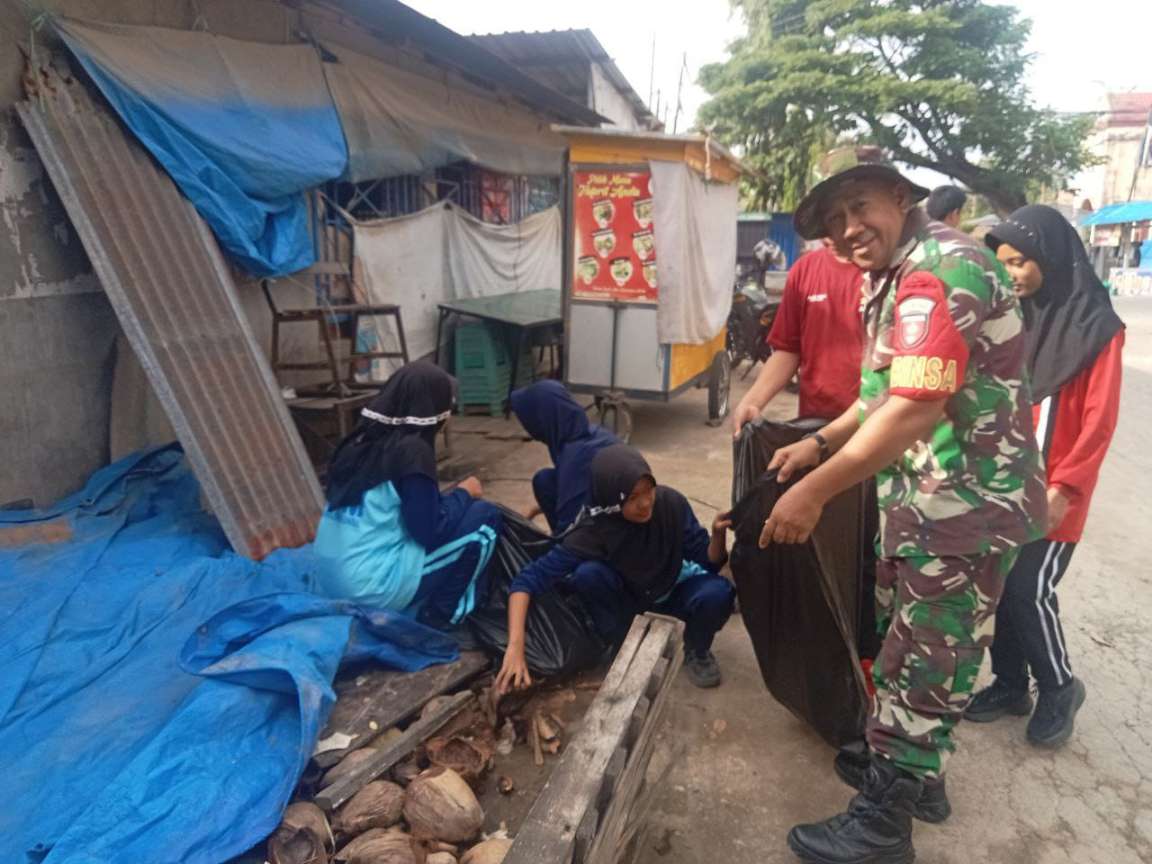 Babinsa Kelurahan Rappang, Serma Syahniawan Dani, bersama siswa SMPN 1 Rappang bergotong royong membersihkan lingkungan dalam karya bakti pencegahan banjir di Sidrap.