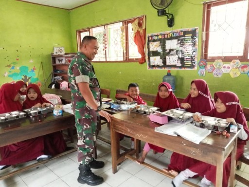 Babinsa Kodim 1420/Sidrap mendampingi siswa SD saat menerima makanan bergizi gratis dalam program pemerintah di Kabupaten Sidrap.