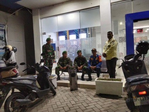 Personel TNI, satpam, dan petugas damkar duduk dan berdiri bersama di depan salah satu titik vital Tanru Tedong saat melaksanakan patroli Siskamling di Kecamatan Duapitue.