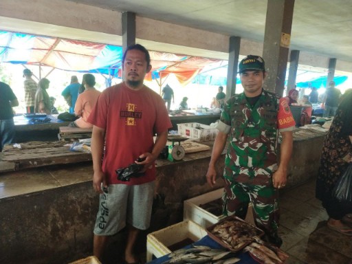 Seorang Babinsa Koramil 1420-07/Baranti bersama seorang pedagang ikan berdiri di area Pasar Sentral Baranti saat melaksanakan monitoring harga sembako.