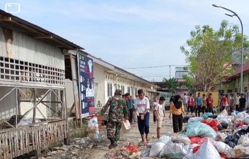 Babinsa memimpin kerja bakti membersihkan tumpukan sampah di Pasar Tradisional Lancirang bersama warga.