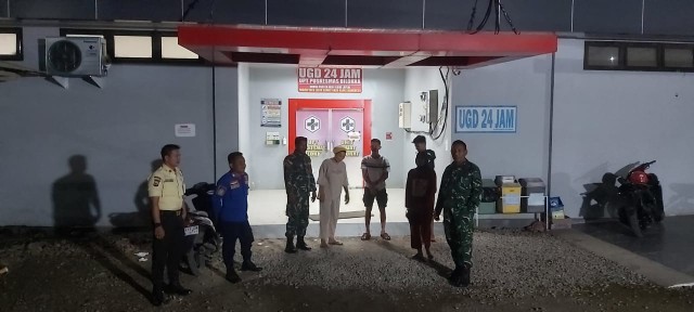 Personil TNI AD bersama warga dan petugas keamanan berdiri di depan UGD Puskesmas Bilokka saat pelaksanaan patroli keamanan wilayah pada malam hari.