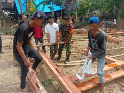 Babinsa Koptu Sahir bersama warga Bilokka mengangkat material kayu saat gotong royong pembangunan rumah bantuan Wakil Ketua Komisi III DPR RI untuk warga bernama Amir di Sidrap.