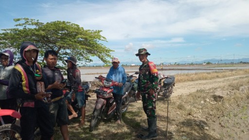 Babinsa Serma Muhammad Ari berdiri bersama para petani di tepi area persawahan Kanyuara, Sidrap, saat melakukan pendampingan program Luas Tambah Tanam.