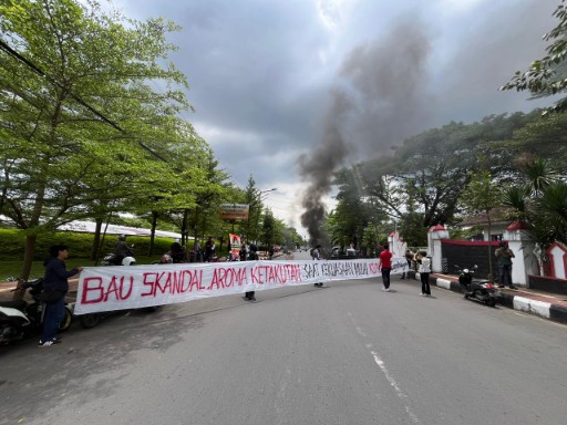 Massa aksi di depan DPRD Gowa membentangkan spanduk panjang dan membakar ban sebagai bentuk protes terhadap isu yang melibatkan Bupati Gowa.